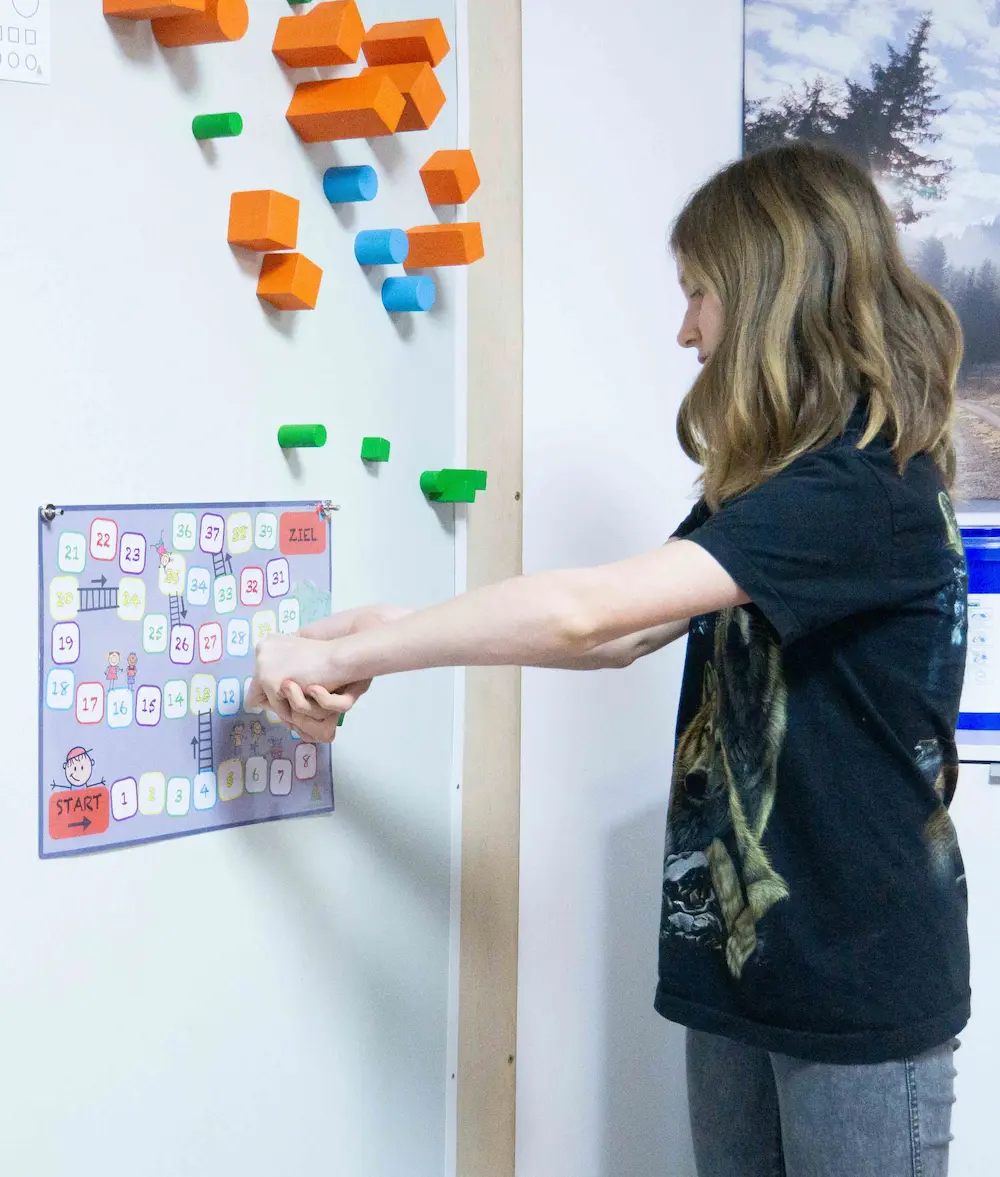 A child points at a magnetic picture board on the wall next to a climbing wall