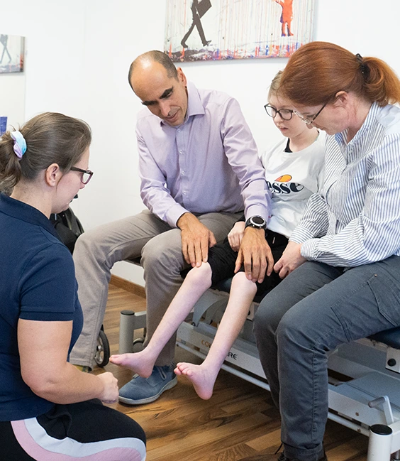 Therapeut:in und Arzt besprechen Therapieplan für Kind mit Orthese
