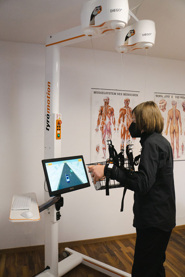 Patientin macht Übungen mit Handroboter