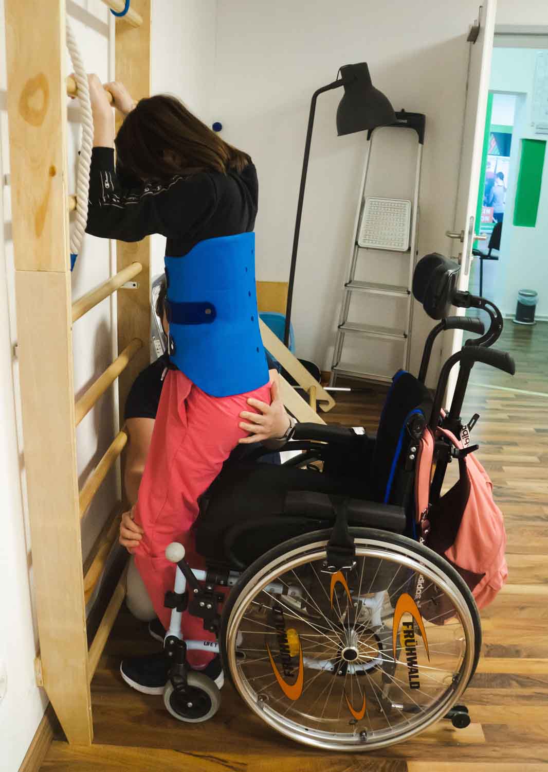 Kind am Sprossenwand und Therapeutin hilft