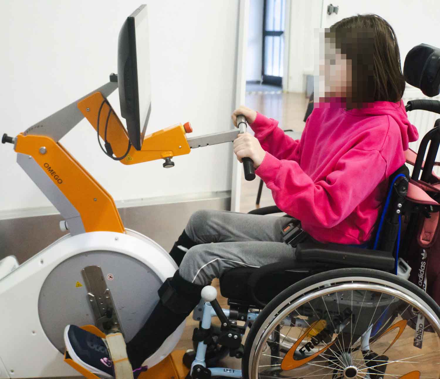 Kind übt am Omego im Rollstuhl spielerisch