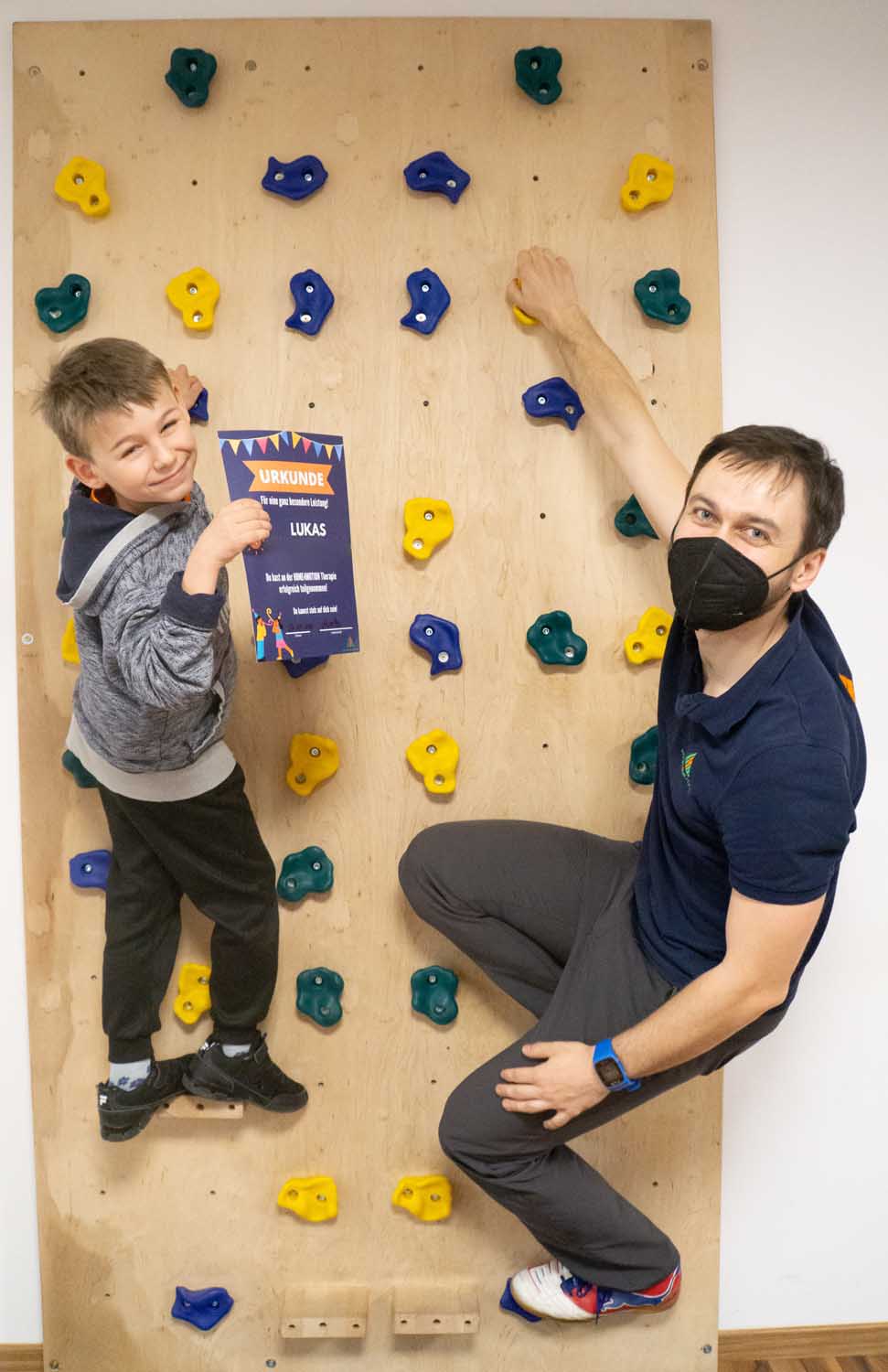 Lukas mit seiner Urkunde und Trainingstherapeut Moritz