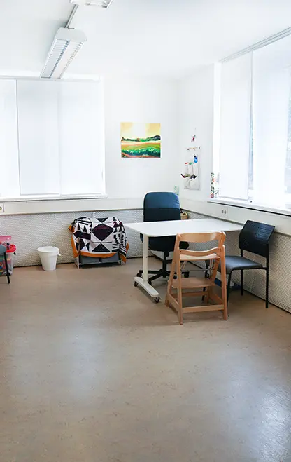 Beratungsraum mit dem Tisch, Kinderstuhl und Sitzgelegenheiten für die Eltern