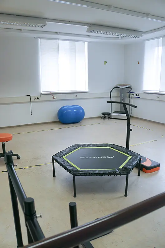 Bewegungsraum mit Trampolin und Gehbarren, im Hintergrund Gymnastikbälle