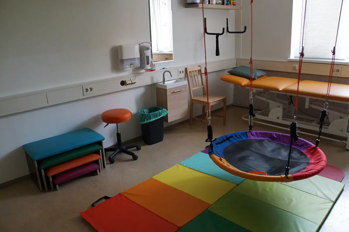 Blick in den Schaukelraum: Nestschaukel, gestapelte bunte Matten und ein Rollhocker