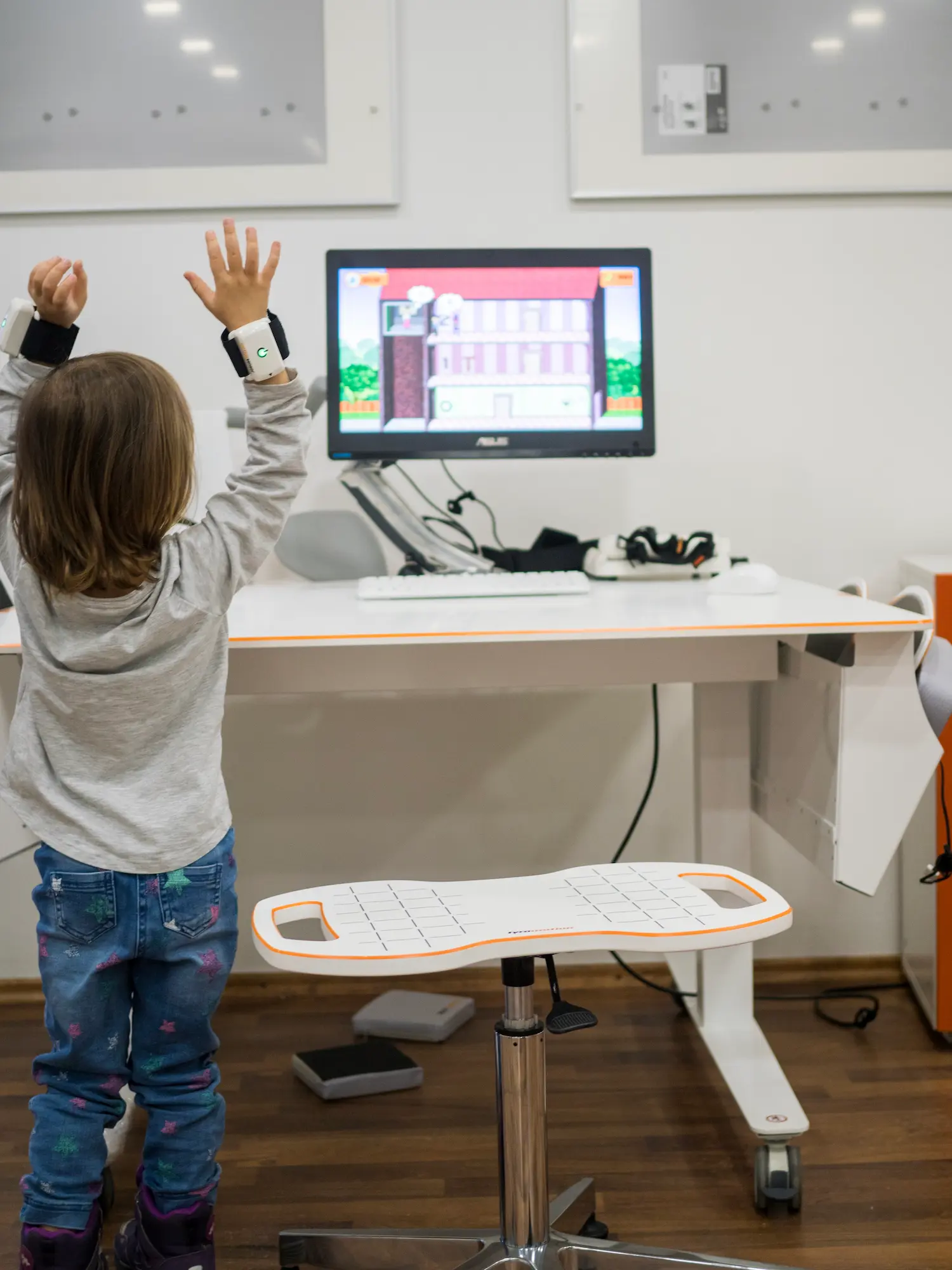 Kind macht Übungen mit Pablo Sensor und Bildschirm mit speziellen Programm läuft