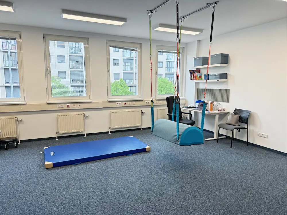Heller Therapieraum in Wien mit blauer Bodenmatte und Deckenaufhängung
