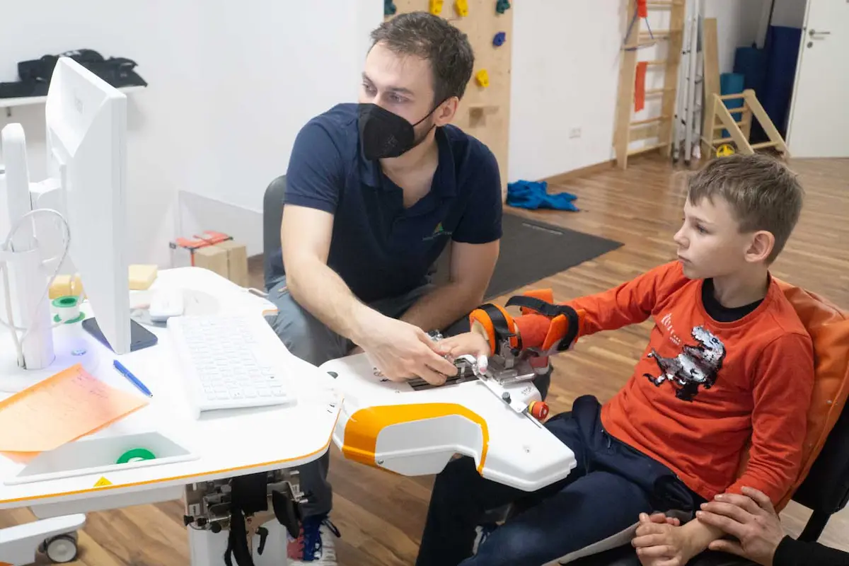 A therapist sets up an arm splint while a child sits alongside