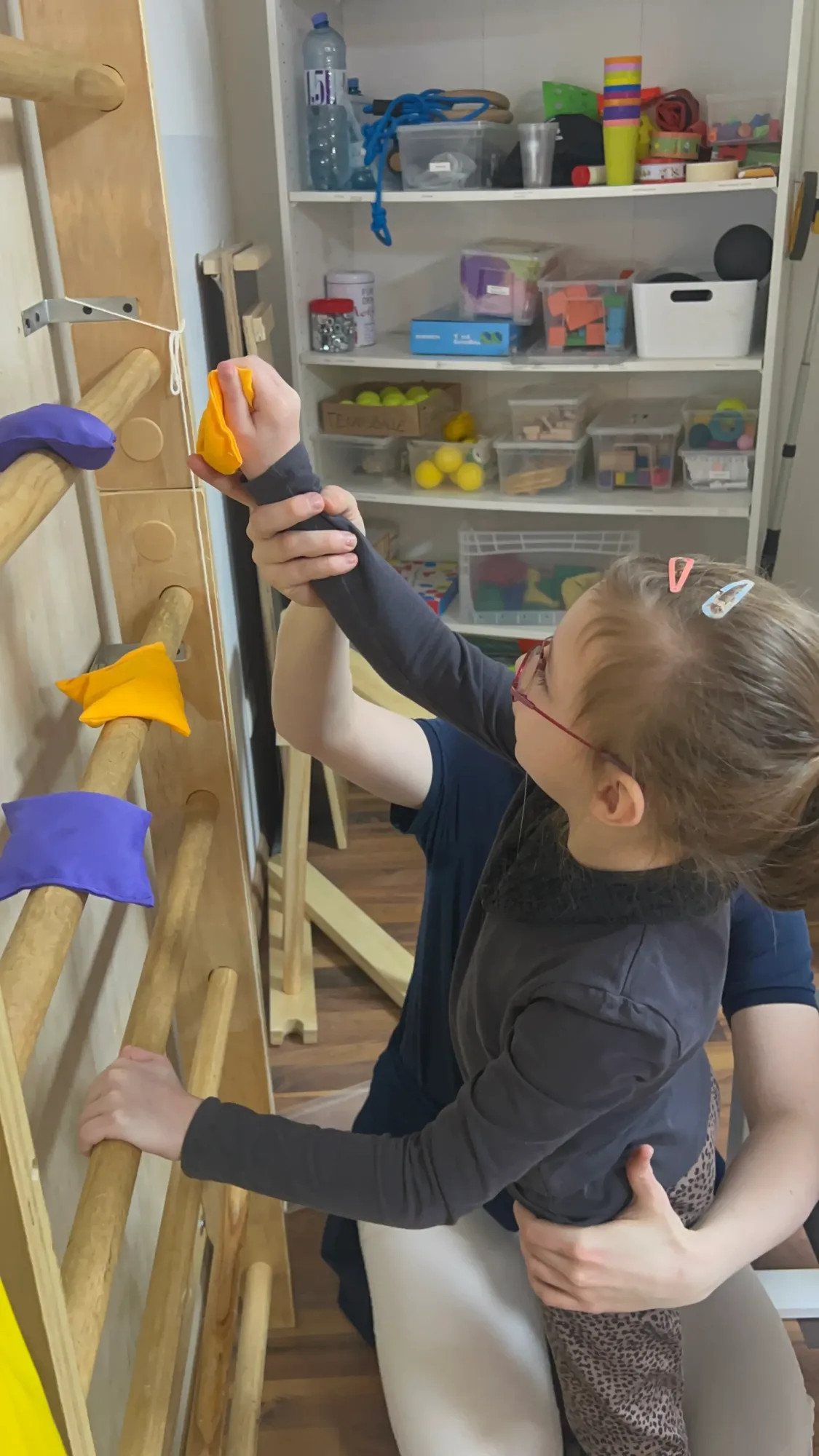 A child stretches for a climbing hold mounted high up